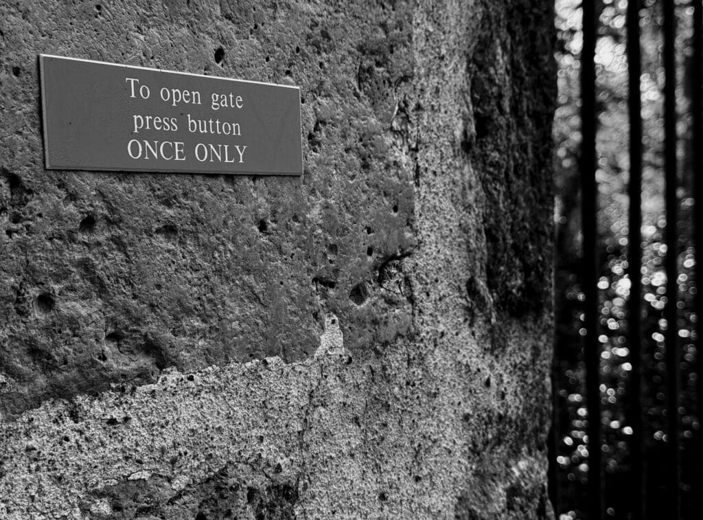 Close-up of a plate fixed to the stone pillar of a property's gate, which reads: 'To open gate, press button' and below in capital letters 'ONCE ONLY'. Freaky.