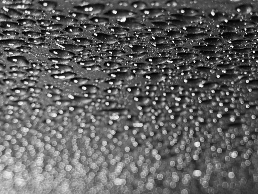 Grox plan sur des gouttes de pluie sur læ capot d’æn voiture.