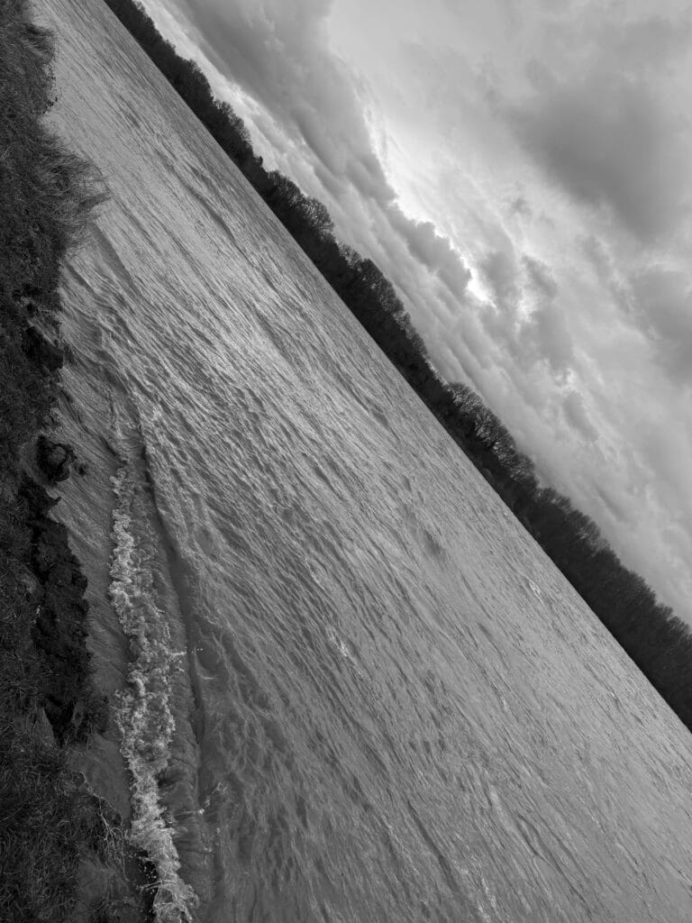 View of a turbulent river, with the skyline slanting from the top left to the bottom right.