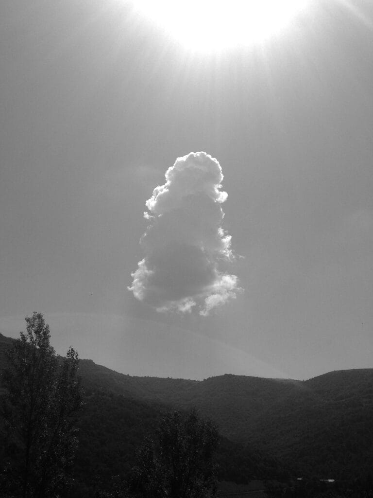 A magnificent cumulus congestus, the only cloud left after the downpour, lit up by the rays of an enormous sun and floating above the rainbow-decorated valley.