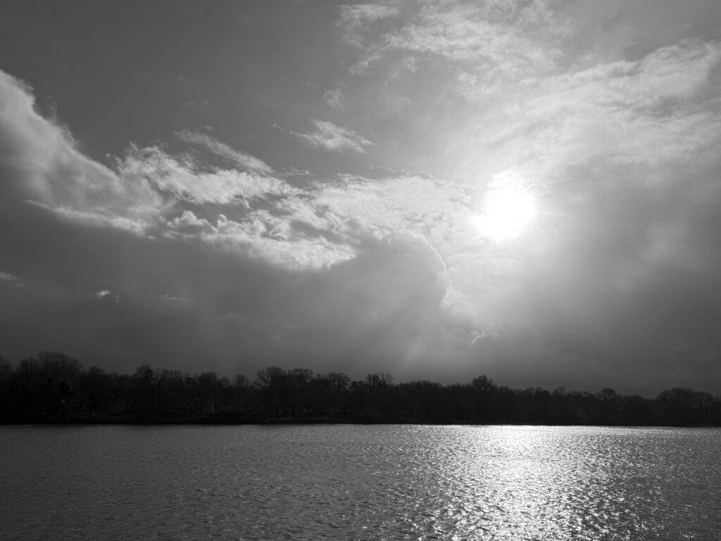 View of a stretch of water and the opposite bank in the cloudy sunset.