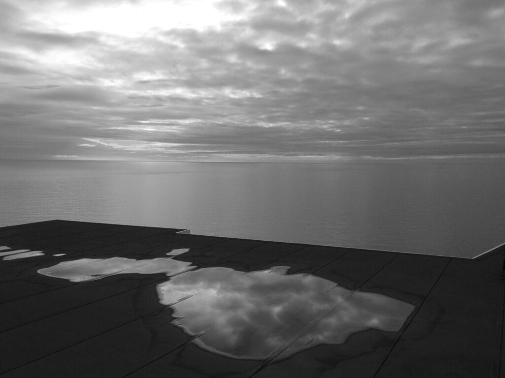 A view of the Irish Sea with puddles on the ground in the foreground.