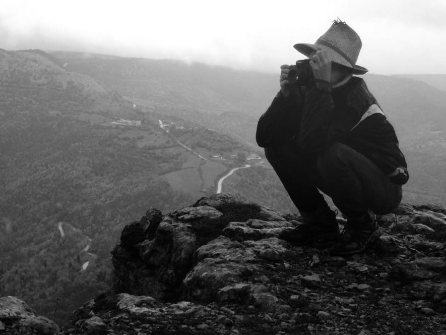 Yours truly photographer, wearing a hat and taking a pic while perched at the top of a cliff on a rainy day.