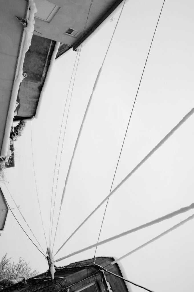 Large gathering of electricity and telephone cables in the village square under the snow.