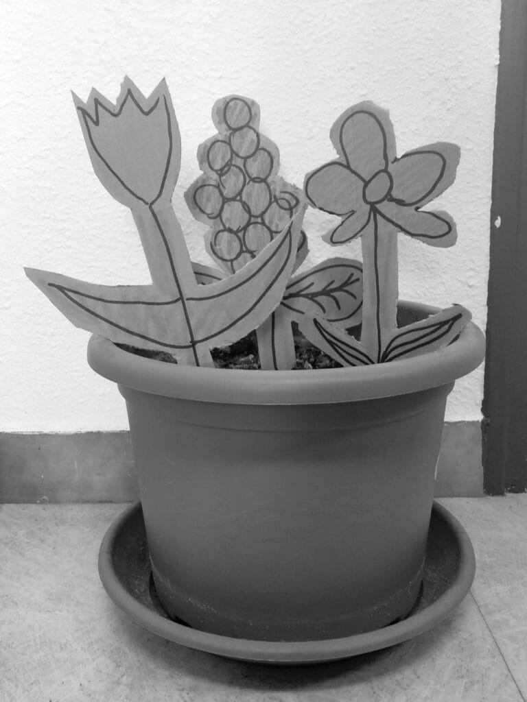 In an office: a flower pot with cardboard flowers planted in it.