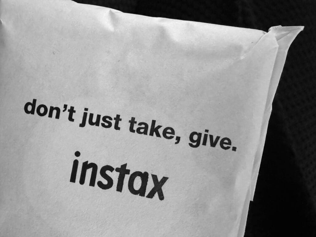 Instax film sleeve with the headline 'don't just take, give'.