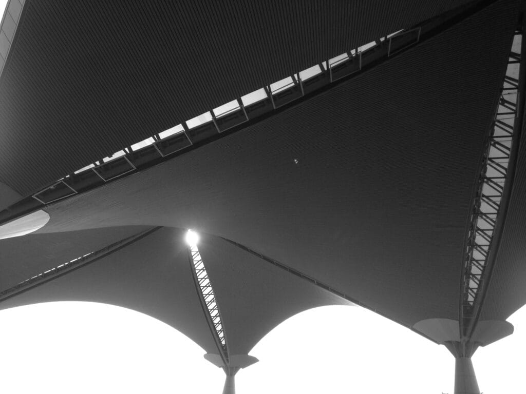 Triangular parasols with holes seen from below, with the sun shining through the holes.