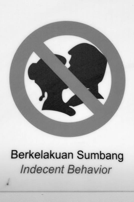 KLCC subway pictogram of a couple kissing crossed out with a prohibition sign reading 'Berkelakuan Sumbang / Indecent Behavior'. So 'indecent behavior' is forbidden.