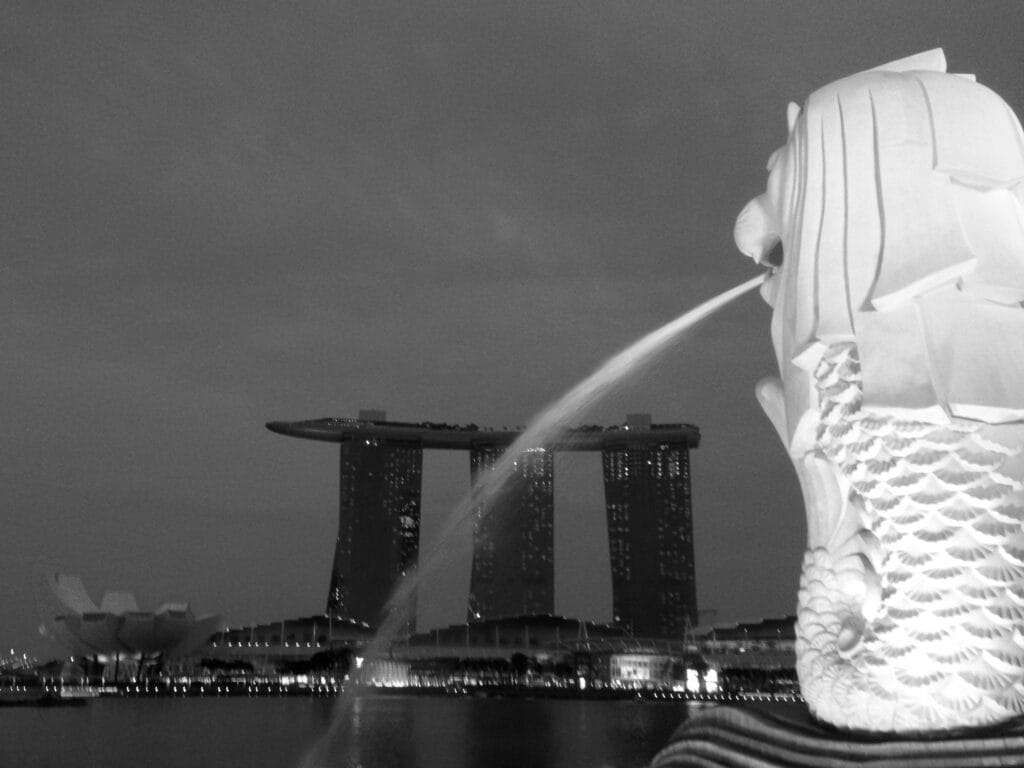 View of Marina Bay by night, with the Merlion statue in the foreground and Marina Bay Sands and the ArtScience Museum in the background.