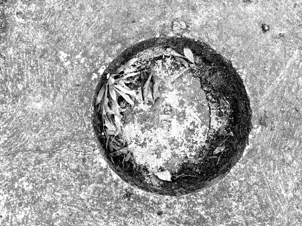 Round place to put a pole on the sidewalk, without the pole inside, as seen from above.