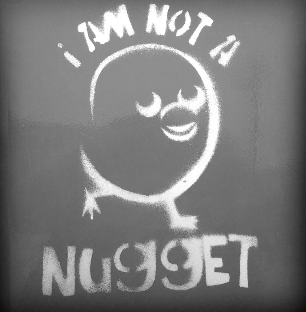 Stencil graffiti of a chicken with the inscription 'I am not a nugget'.