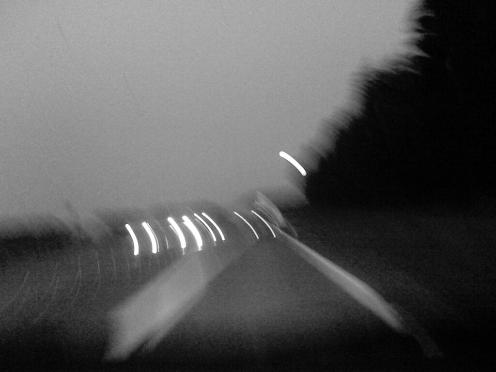 Vue d’æn route læ nuit prix à travers læ pare-brise, les voitures en face phares allumæs. Flou de bougé.