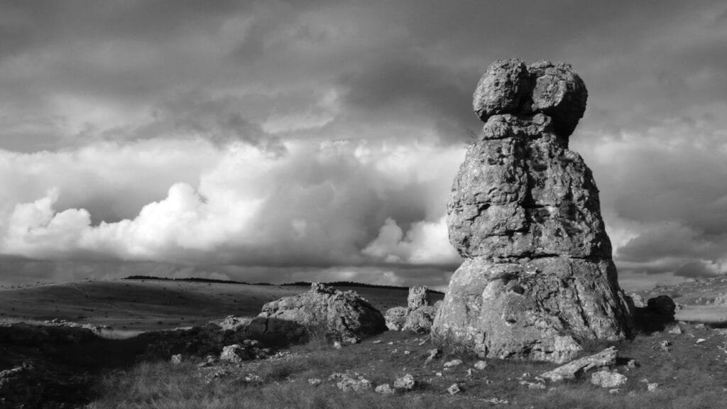 A rock from the Nîmes-le-Vieux blockfield overlooks the expanse of the plateau and the cloud-topped horizon.
