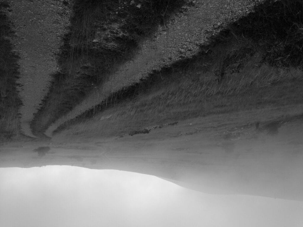 A long road stretches across a deserted limestone plateau, shrouded in mist. The image is upside down.