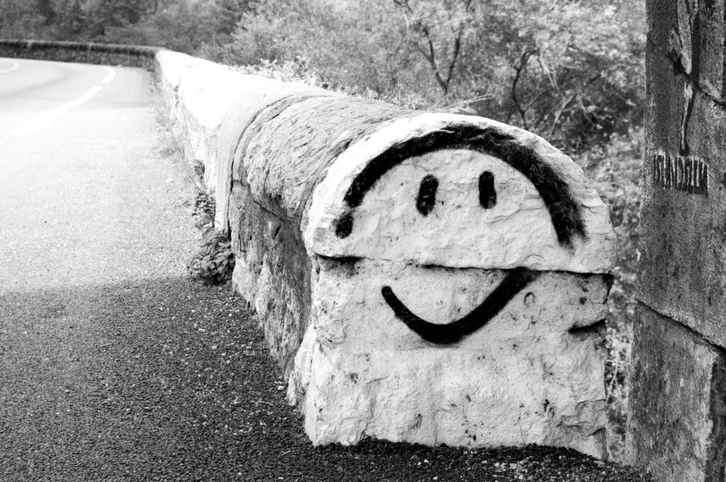 Graffiti of a smiling figure at the end of a parapet.