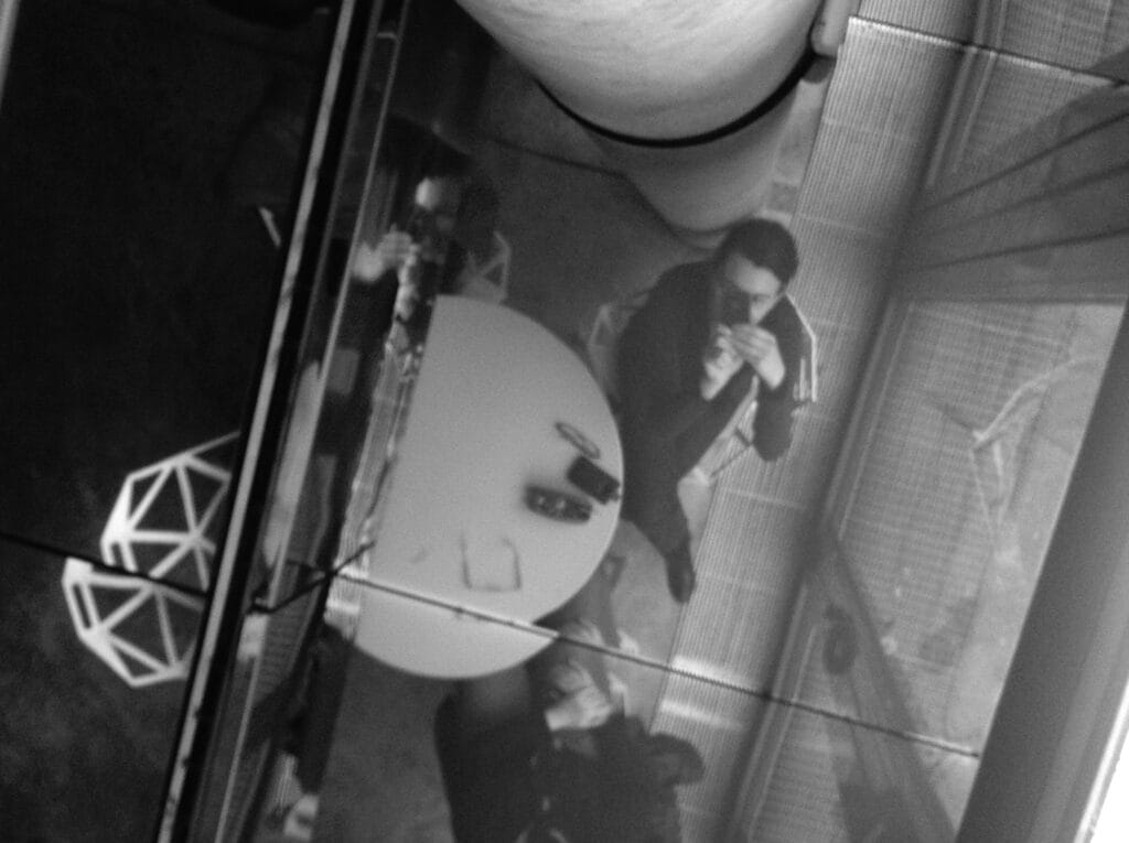 Autoportrait dal photographe dans læ vitre dal plafond dal café dal musée dal Quai Branly à Paris.