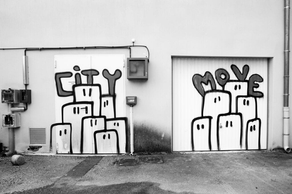 Graffiti on garage doors depicting buildings with eyes and the text ‘city move’.