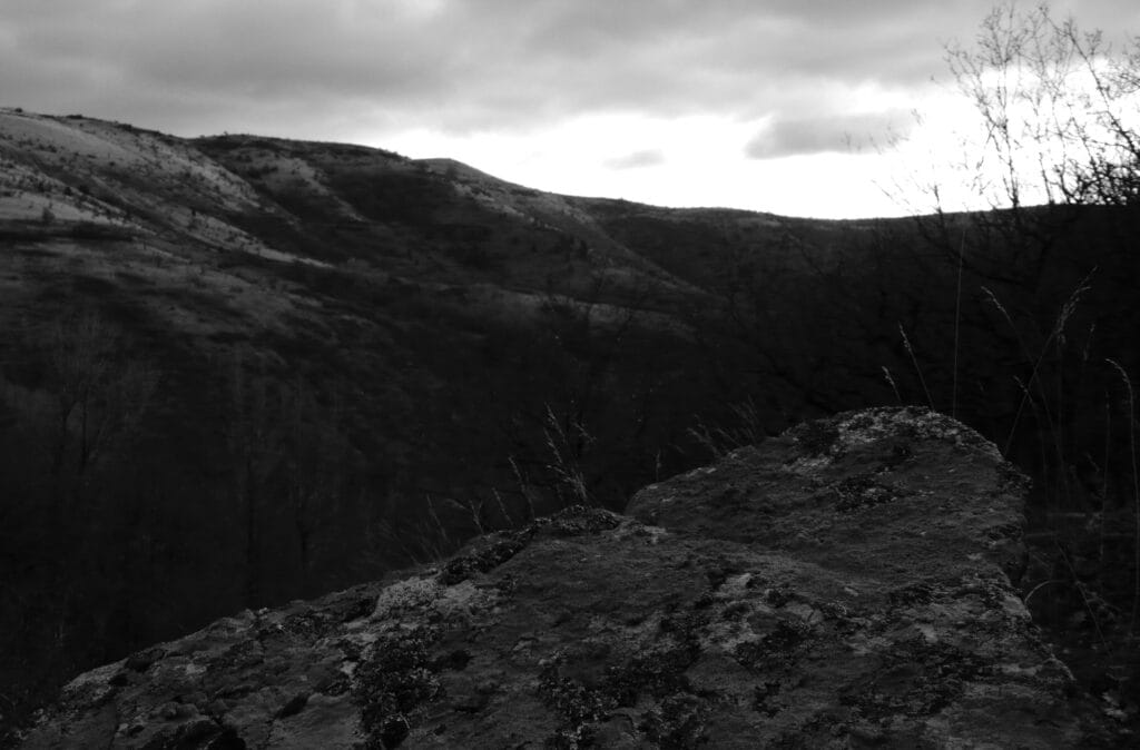 A rock jutting out into the void, at the top of a hill in a landscape of high plateaus.
