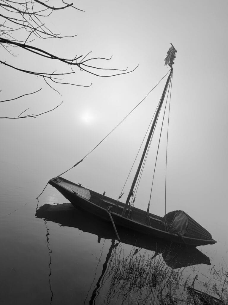 A typical Loire boat on the Loire River, parked near the bank in thick fog.