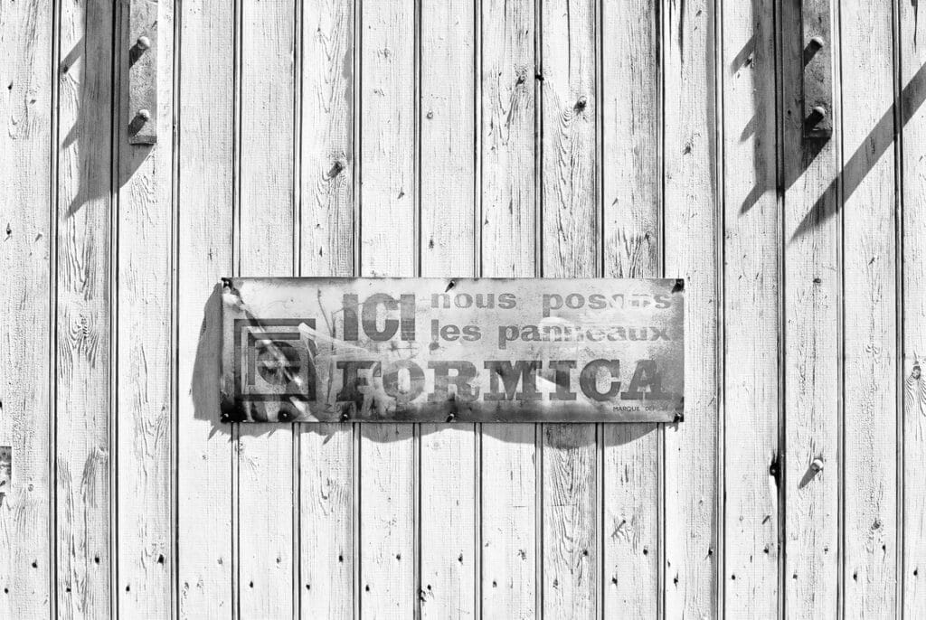 A sign on a barn door reads: ‘Here we install Formica panels’.