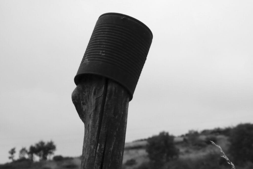 Rusty tin can on fence post.