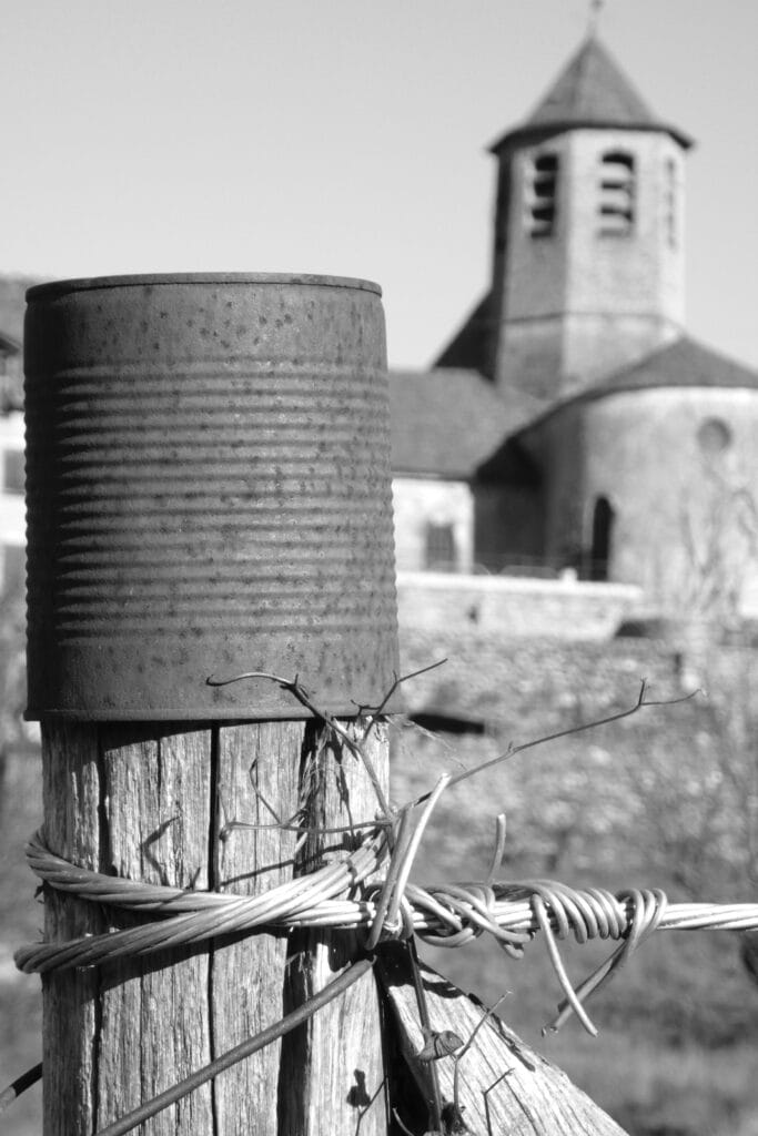 A squat church steeple with a fence post topped with a tin can in the foreground.