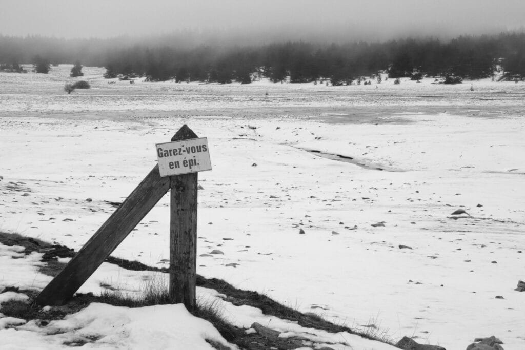 A 'Park at an angle' sign was placed next to a snow-covered, deserted pond.