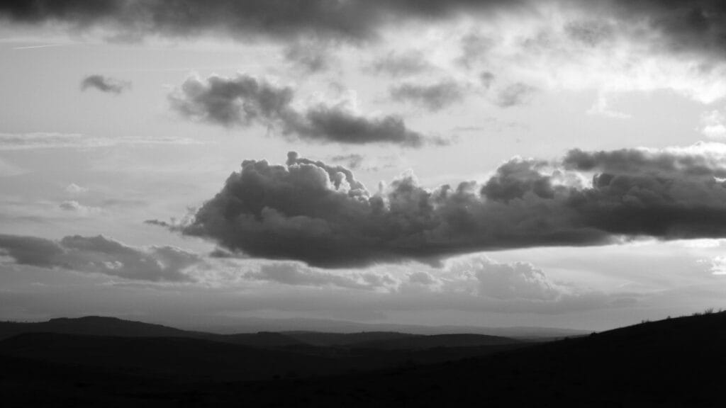 An elongated cumulus cloud resembling a dragon waves above a horizon of plateaus.