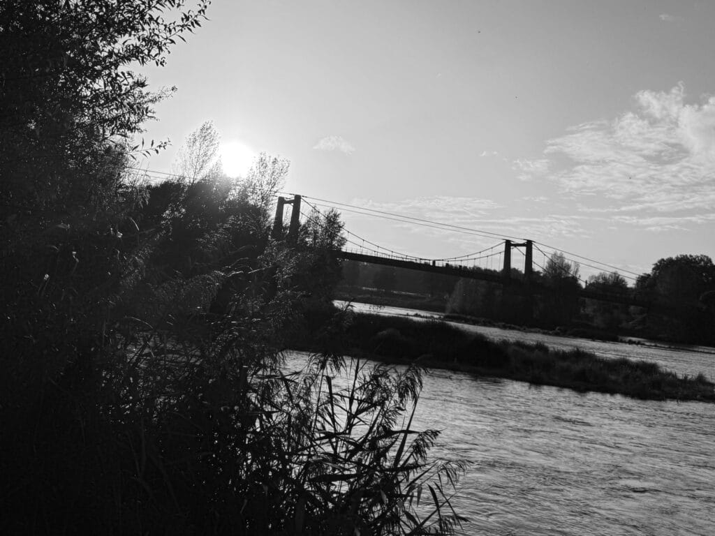Suspended bridge over the river in the golden light of the setting sun.