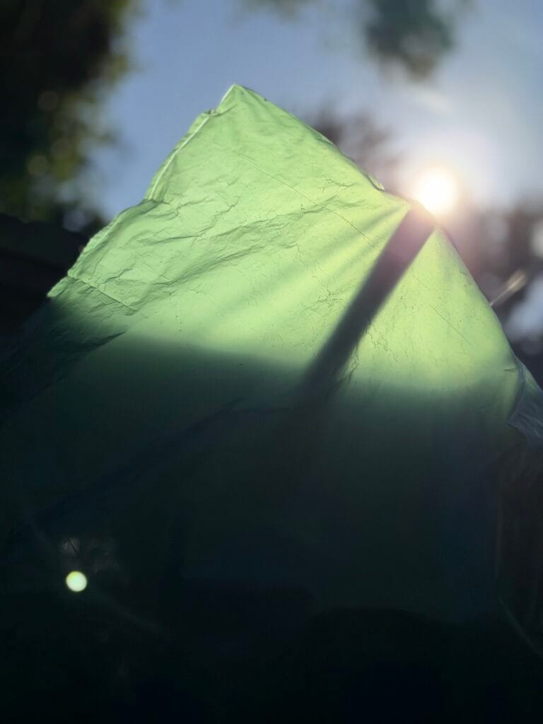 The rising sun peeking out from behind a plastic sheet.