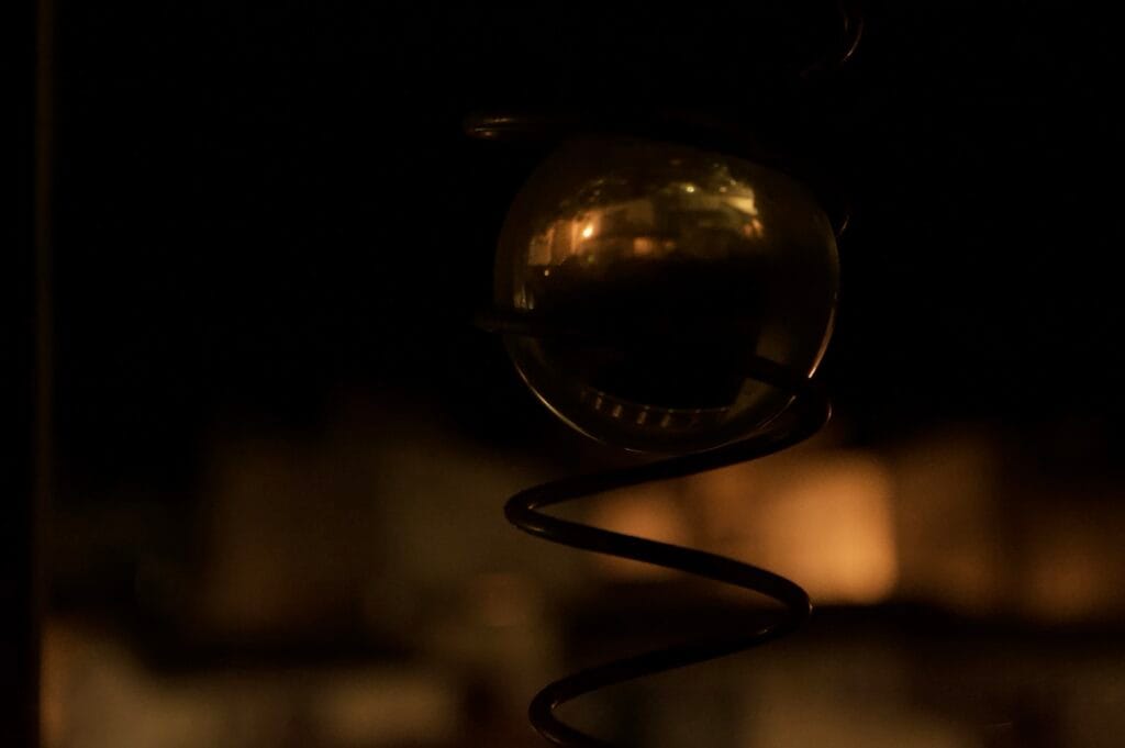 A glass sphere encased in a metal spiral, reflecting the image of a village at night.