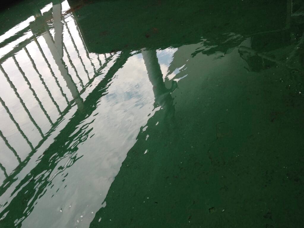 A reflection of the sky and the outline of a boat on the wet deck.