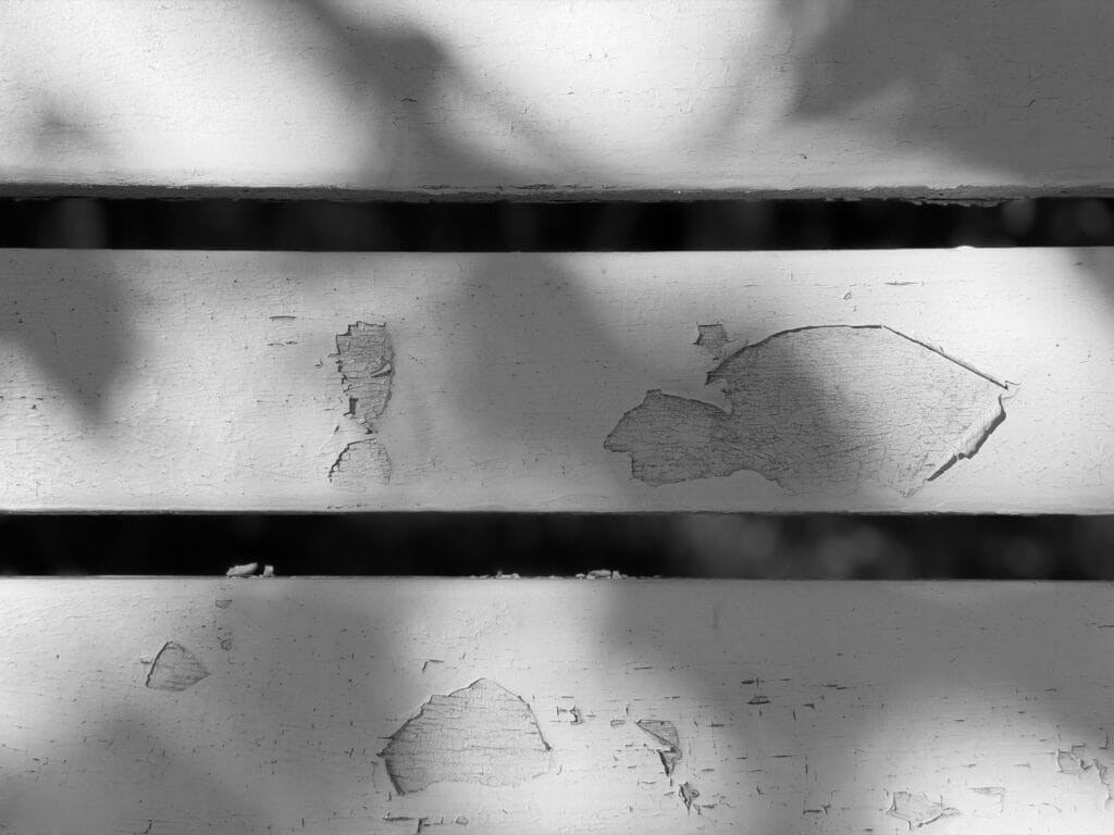 A wooden garden bench with peeling paint.