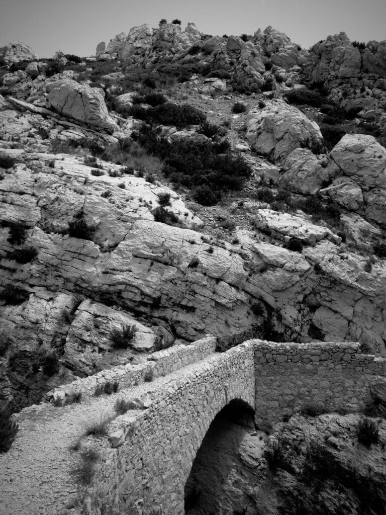 A rocky landscape. A stone bridge spanning a deep gorge between two limestone hillsides.