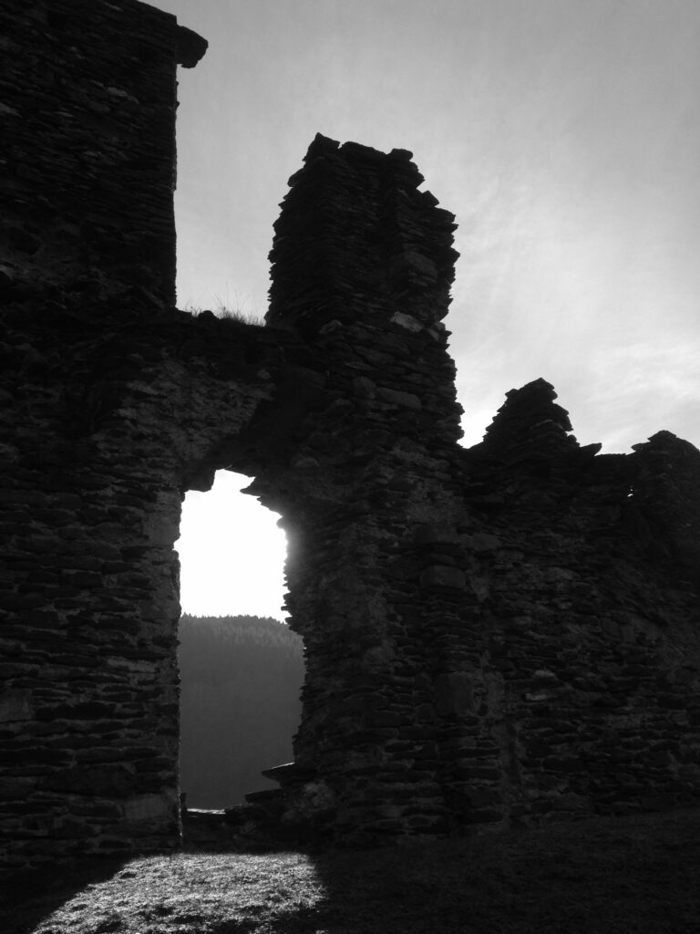 Walls of a ruined castle backlit in the sunset.