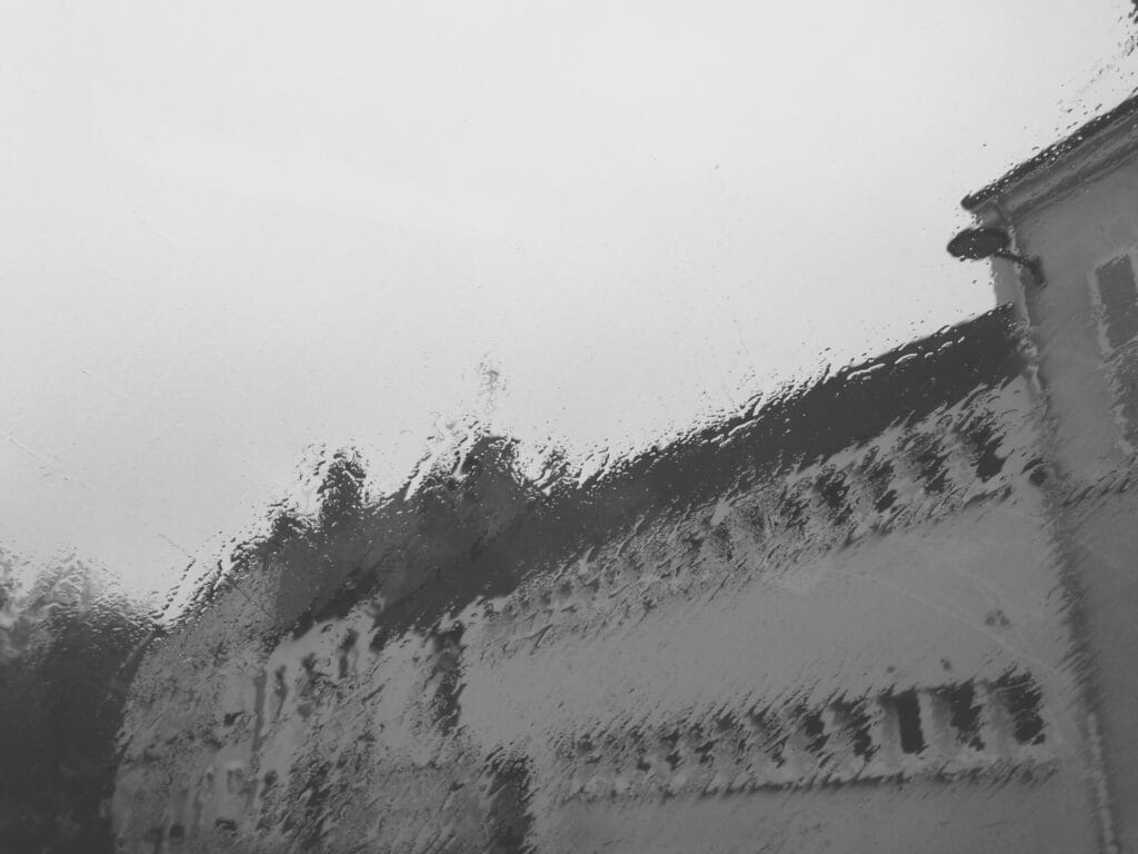 An austere building seen through a rain-swept window.