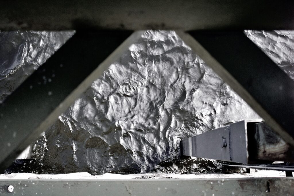 Water seen through the metal structure of a bridge.
