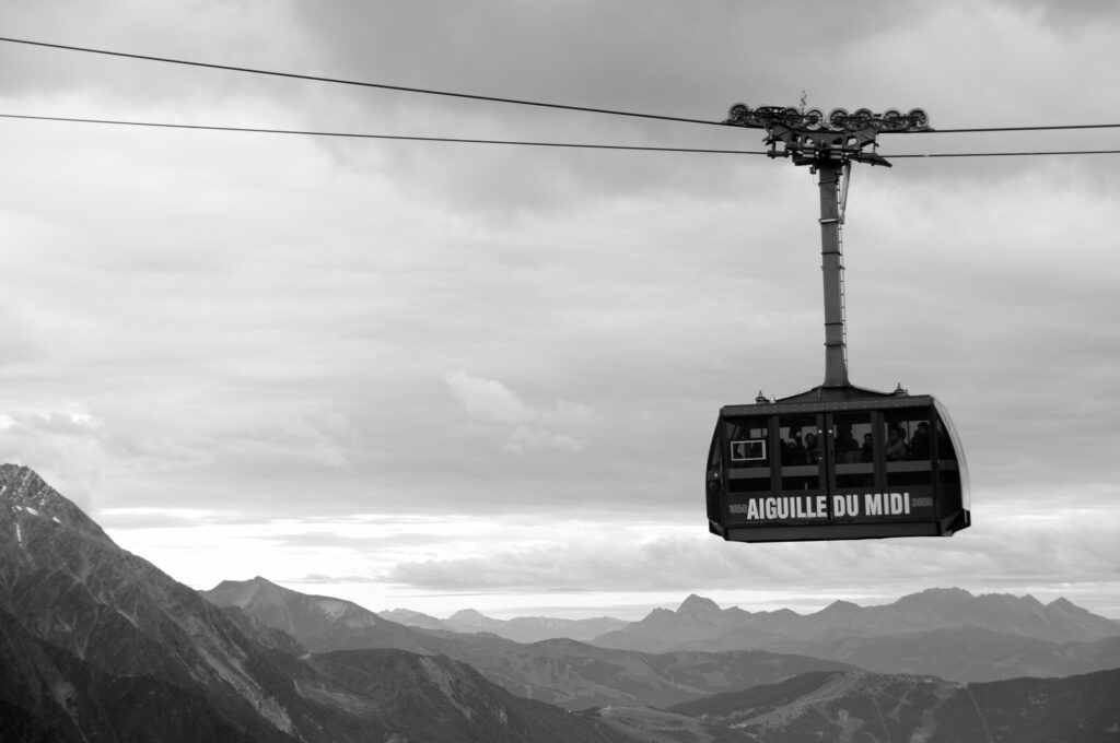 Aiguille du Midi cable car cabin against a cloudy sky, with mountains in the background.